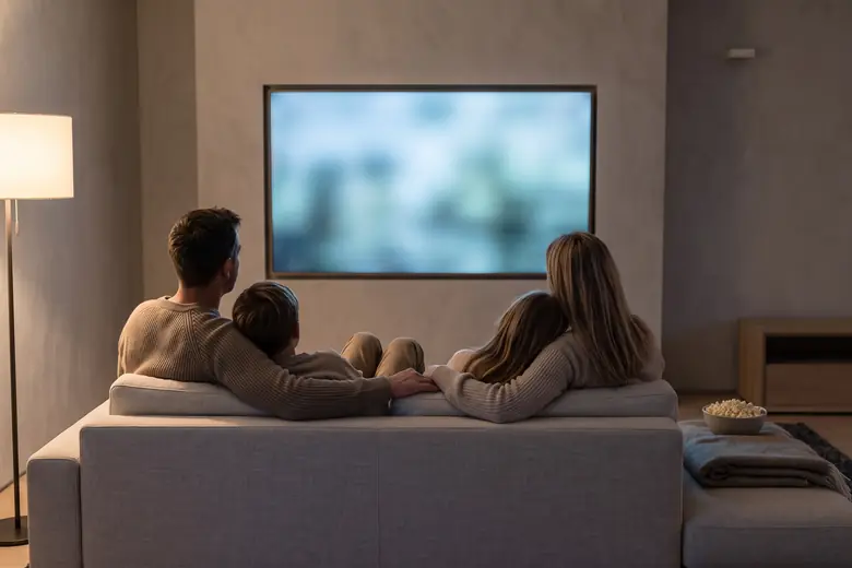 Family watching a film together in a living room equipped with a Bannister Acoustics 8800 Elite Series home theater system